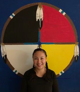 Dr. Pearl Yellow Old Woman-Healy with braided hair and standing infront of a medicine wheel.