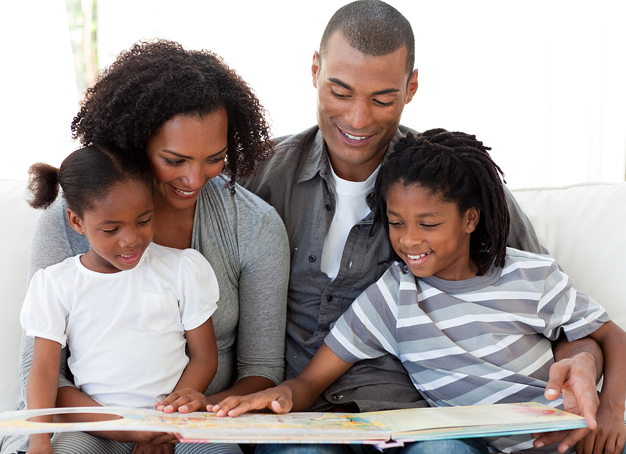 Family with mom, dad, son and daughter reading a storybook.
