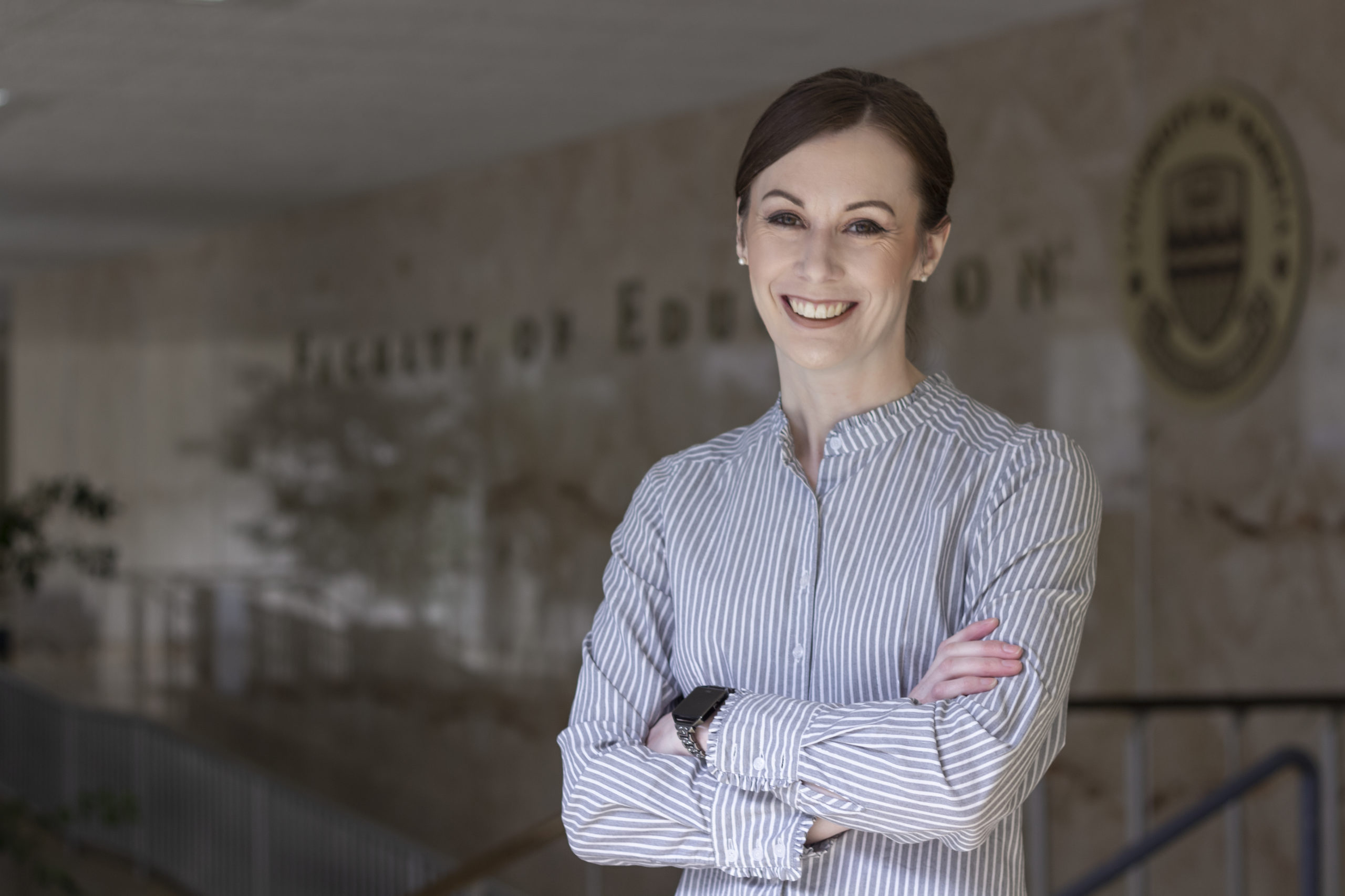 Heather Brown, smiling with her arms crossed. Wearing a blue button-down shirt.