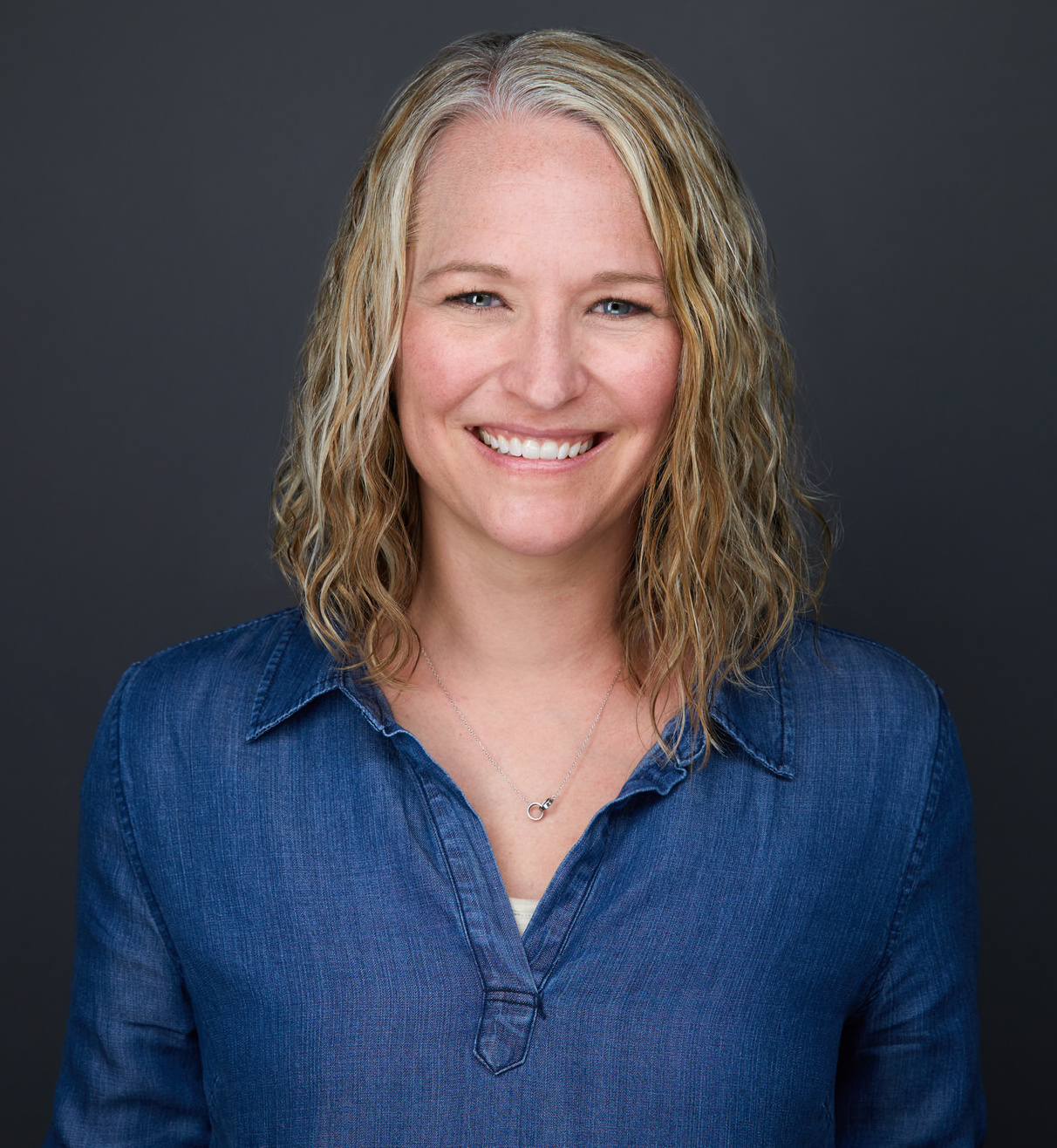 Sandy Thompson-Hodgetts, smiling, wearing a blue button down shirt.