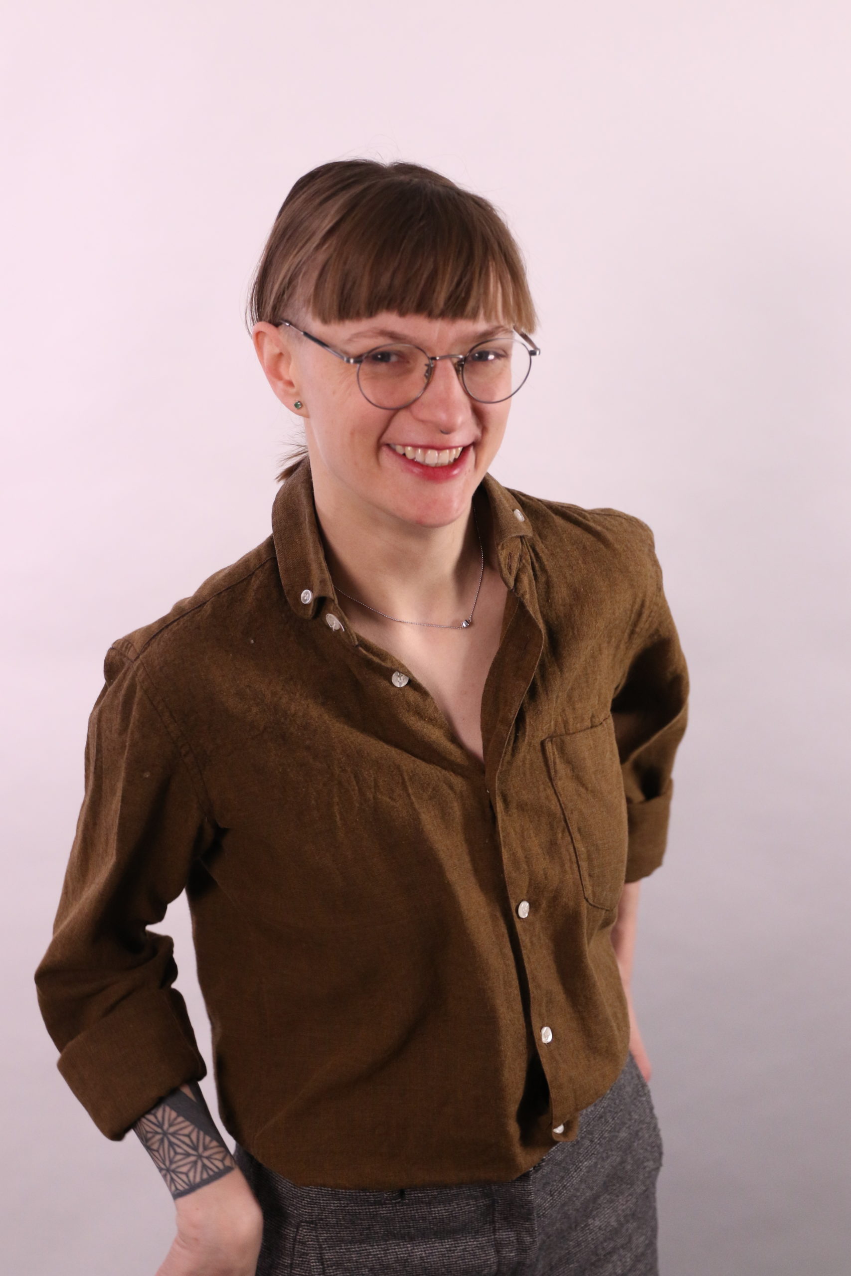 Brooke Leifso, standing, wearing glasses and a brown button down shirt.