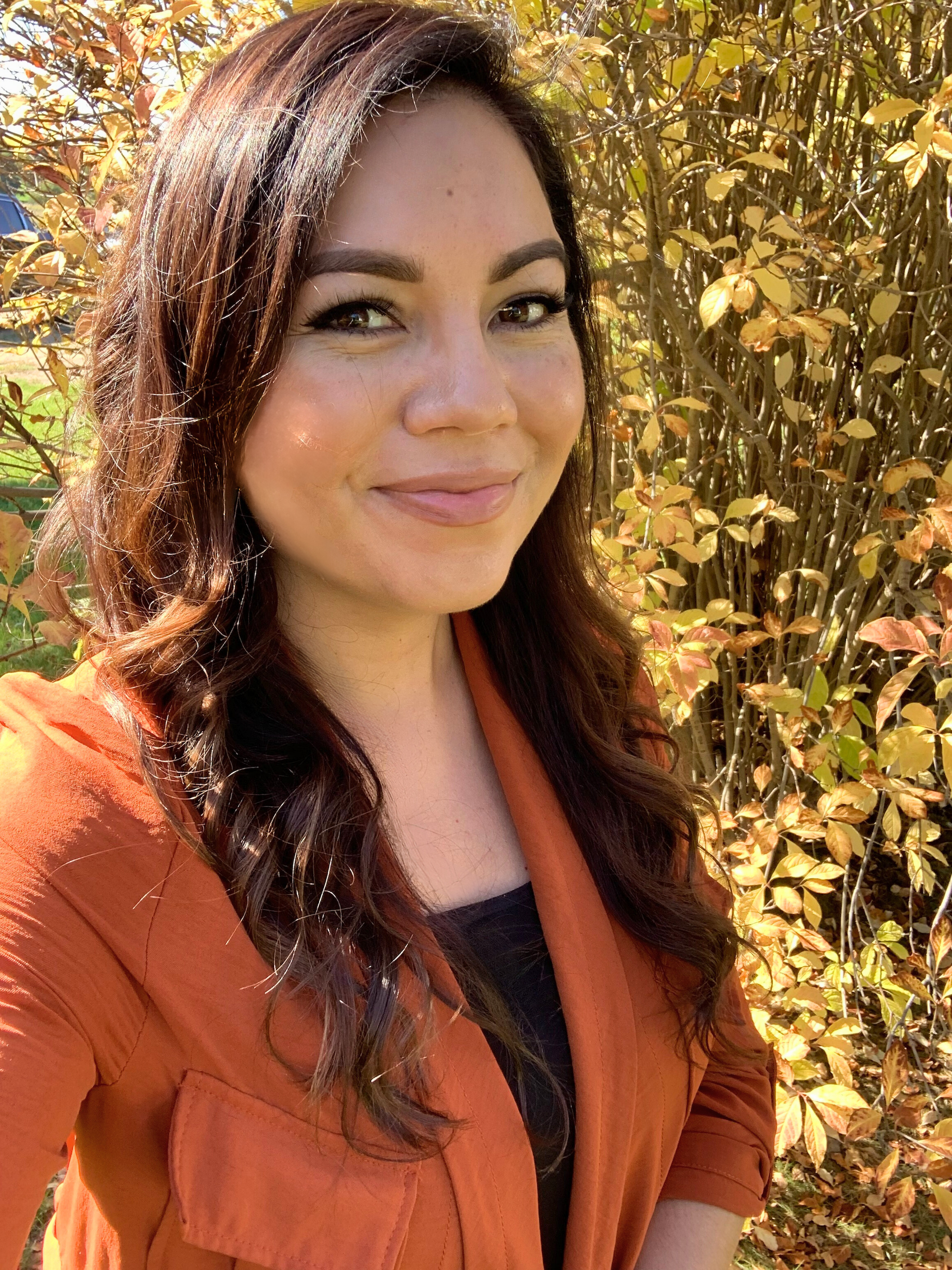 Kristen Swampy standing outside while smiling, wearing an orange blazer.