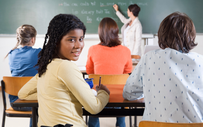 Classroom or college students with the teacher writing on a chalk board.